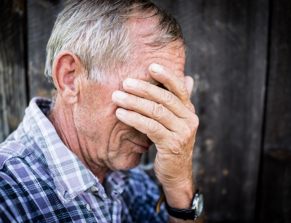 Desperate senior man suffering and covering face with hands in deep depression, pain, emotional disorder, grief and desperation concept